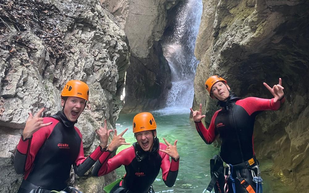 Trois participants tout sourire devant une cascade et sa vasque, partie basse du canyon de Montmin