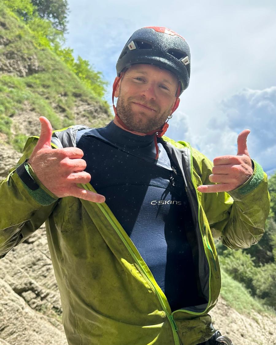 Yoann, casque sur la tête, fait le signe shaka au départ du canyon